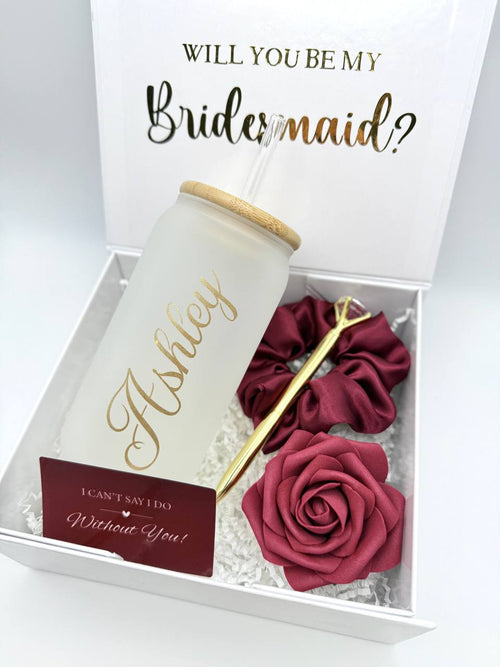 set 2. Burgundy theme bridesmaid proposal gift box with “Will you be my bridesmaid?" on the inner lid, magnetic lid. with personalized glass cup, jewelry box, a scrunchie, a gold colored metal diamond pen, a foam rose head, a "I can't say I do without you" card, a straw