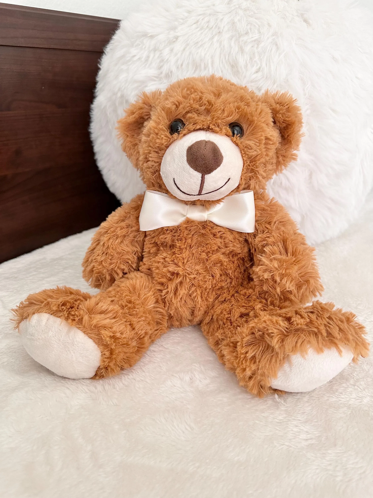 brown plushie bear with a beige colored bowtie 