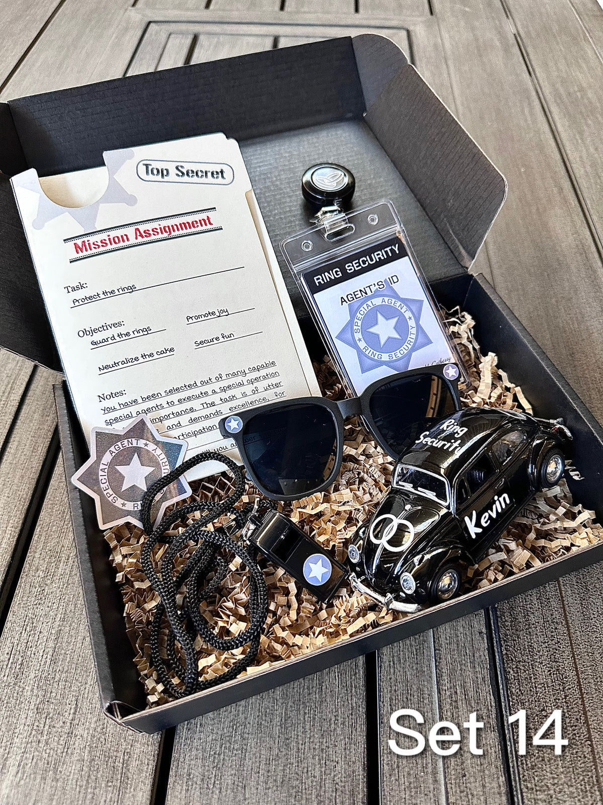 ring security proposal box. open box. set 14 includes a "mission assignment" card, an agent ID badge, sticker, sunglasses, die-cast car personalized with a name, whistle, and brown paper filler. 